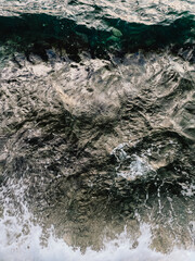 Dark green ocean water displaying white foam and small waves, creating textured natural background with ripples that evoke a sense of tranquility and serene beauty. Dark green seawater with white foam