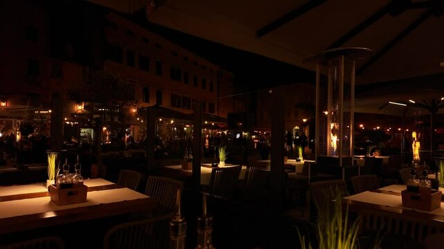 Gas patio heaters with beautiful yellow and orange fire flames at night. Outdoor heating system for cozy and romantic cold evenings. Practical and useful decoration for event venues and restaurants.