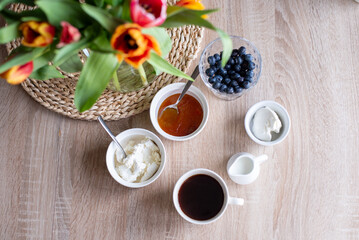 A bouquet of tulips in a glass vase in the living room and breakfast with coffee, cottage cheese and berries
