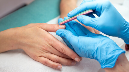 A manicurist performing a Japanese manicure on a client