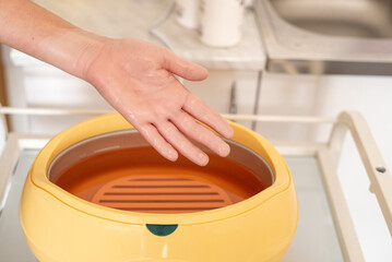 Paraffin therapy. Woman dipping her hand into a paraffin wax bath.