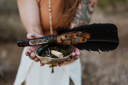 Fototapeta woman holding a feather and shell in desert landscape
