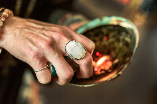 Woman lighting sage in a shell