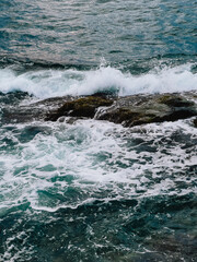 Ocean waves crashing against rugged rocks, creating dynamic splashes of white foam amidst vibrant turquoise waters in stunning seascape, raw beauty of nature. Powerful waves smashing rocky coastline