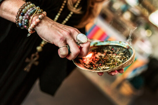 Woman lighting sage in a shell
