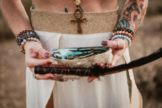 Woman holding shell and feather in desert