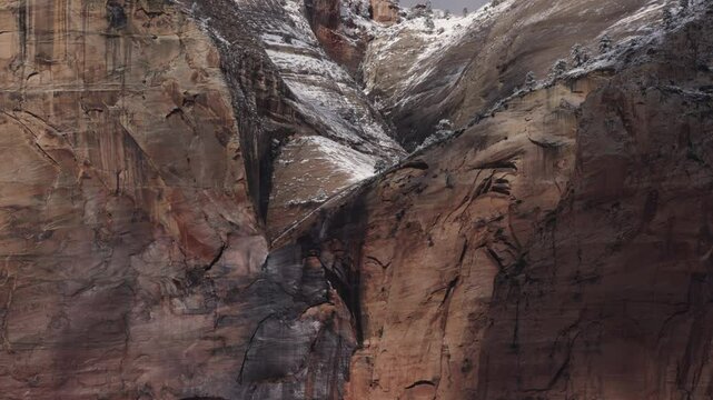 An ephemeral waterfall created by melting snow pours down a steep sandstone slope and over the edge of a high cliff where the wind catches it and flings the water high into the air in Zion NP Ut. USA.