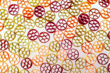 Background with texture dry italian pasta Rotelle. Different flavors and colors: egg, spinach, carrot, pepper.