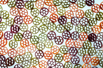 Background with texture dry italian pasta Rotelle. Different flavors and colors: egg, spinach, carrot, pepper.