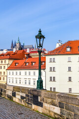 Fototapeta premium A street lamp is lit up in front of a building with a red roof in Prague Czech Republic