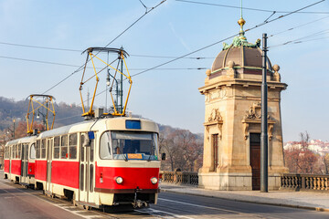 A red and white train is traveling down a street next to a building in Prague Czech Republic