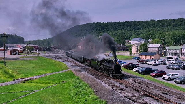 A classic steam train departs from a quaint town, moving along picturesque tracks surrounded by lush greenery and rolling hills.