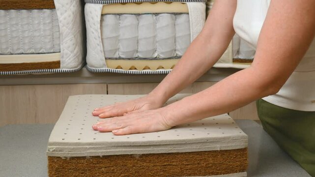 Mattress filler. A mattress sample is in the woman's hands. Independent spring blocks and fillers made of coconut coir, foam rubber, algae, cotton in a cotton cover