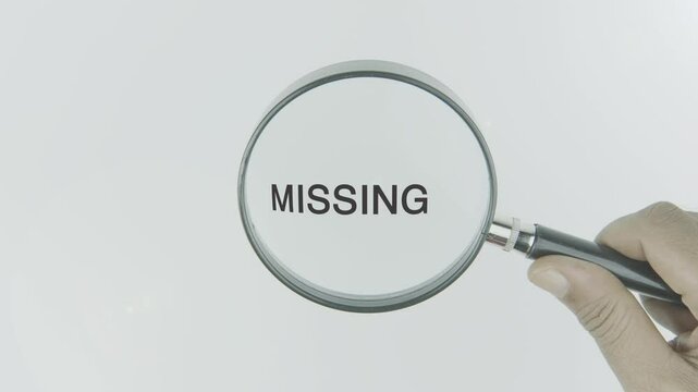 Missing text or word highlighted by a magnifying glass in a hand on a white background, symbolizing absence, search, and the pursuit of what is lost or incomplete
