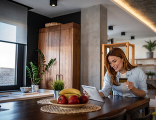 Woman making online payment using digital tablet and credit card at home