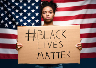 Mass ptotests in USA. Black girl standing with blank cardboard over american flag
