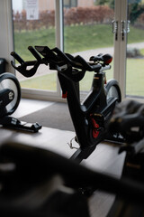 A spin bike is in a gym with a window behind it