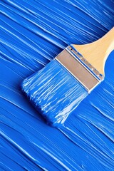 Close-up of a painter applying vibrant blue paint with a wide brush for a professional finish in an artistic setting