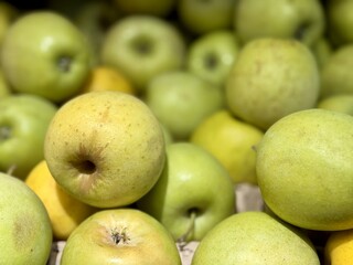 A mound of large green coloured apples in boxes is displayed in the window of the supermarket's vegetable stand, demonstrating organic, vegetarian and healthy food. Close-up