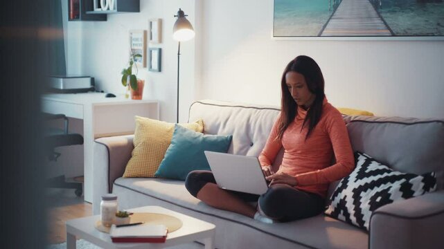 A young beautiful mulatta girl uses a laptop at home. It feels happy. Contemporary design. Shot on RED Epic Camera.