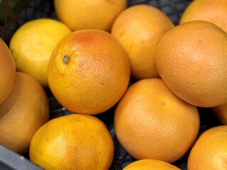 A box of ripe, fresh yellow oranges is for sale on the shelf of a fruit supermarket. Close-up