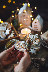 Concept of christmas craft, family leisure time together. Woman holding homemade baked gingerbread cookies with white frosting. Holiday food, fun. Cozy atmosphere, festive home interior