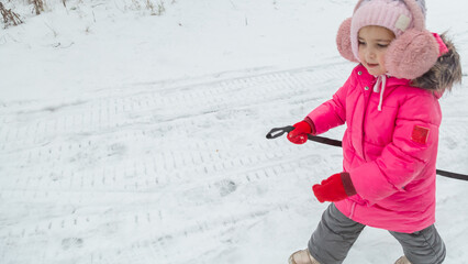 child will have fun in the beautiful winter nature with snow-covered trees. Children walk along a...