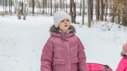 Little girl on snow tubing at winter day
