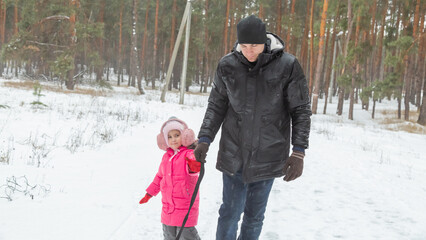 Child girls with dad riding snow tube on sunny winter morning. Funny games on winter vacation.
