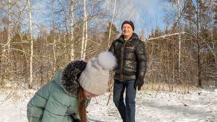 Playful family enjoying snowball fight in snowy winter park