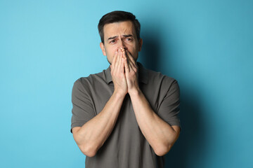 Sad man crying on light blue background