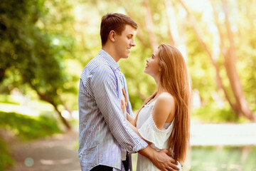 Fototapeta premium Carefree millennial couple embracing and looking at each other outside