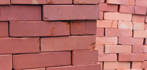 Obraz premium Close up view of minor damage on bricks stacked in cubic columns. Stacked bricks begin to crack and crushing in a hard piles 