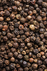 Whole black peppercorns close-up.