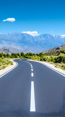 Winding road leading to mountains under a vibrant blue sky