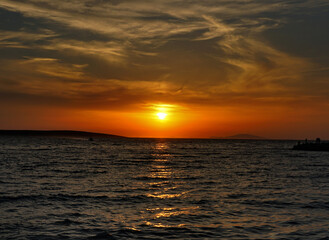 Dramatic summer sky during vivid orange sundown at the seaside