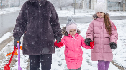 Little girls walking with his grandmother in the snow in winter