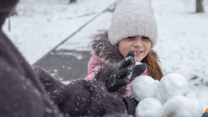 Grandmother with grandchildren in warm clothes playing outdoors in winter park, enjoying snowy...
