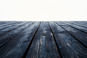 Dark stained wooden planks recede into a blurred white background creating a stark contrast and a sense of depth.