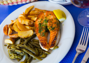 Salmon fillet baked with potato, garnished with braised green beans and slice of lemon