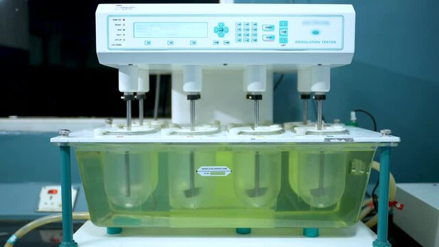 tablet dissolution test apparatus working condition close up. a scientific instrument dissolving tablets in a science instrumentation chemistry laboratory. tablet dissolving machine	