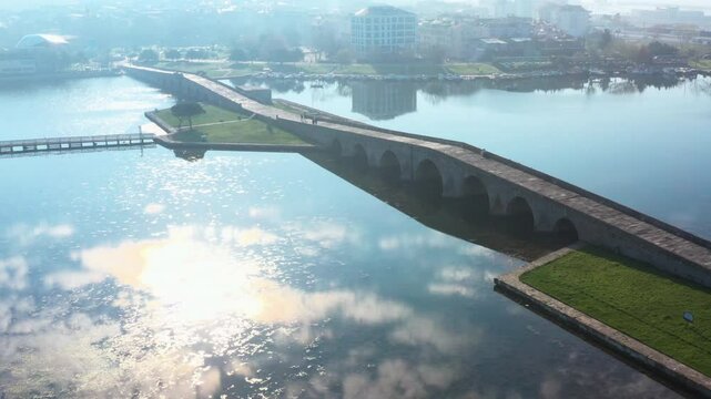 The unique view of the historical Kanuni Sultan S&uuml;leyman Bridge in a foggy atmosphere. The stone texture of the bridge and the lagoon lake. Drone circling over the bridge.