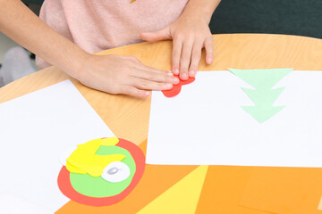 Girl making art project at table indoors, closeup