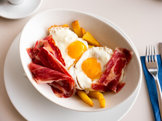 Delicious scrambled eggs with ham and french fries