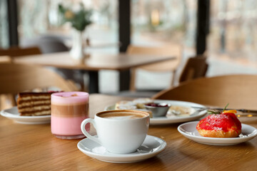 Aromatic coffee and delicious desserts served on wooden table in cafe