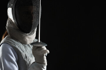 Fencer with epee on black background, space for text