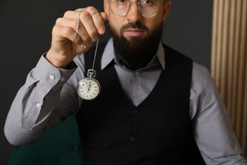 Hypnosis session. Man swinging vintage pocket watch indoors, closeup