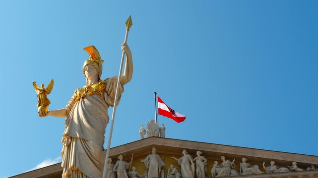 Majestic pallas athena statue, holding nike, the goddess of victory, stands tall against a clear blue sky, with the austrian flag waving proudly atop the austrian parliament building in vienna