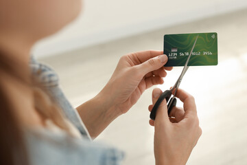 Woman cutting plastic credit card indoors, closeup