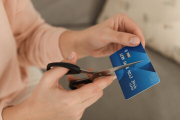 Woman cutting plastic credit card indoors, closeup